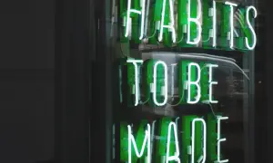 Zielone neony "HABITS TO BE MADE" przypominają o psychologii systemu nagród i kar, który kształtuje nasze nawyki.