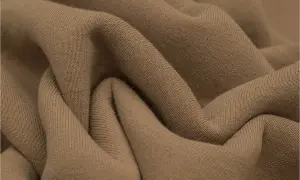 Miękka, drapana tkanina wełniana w odcieniu camel. Delikatne zagniecenia podkreślają jej fakturę.