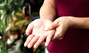 Mano che si tocca il polso, forse per un sintomo di polineuropatia.