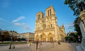 Vue de la cathédrale Notre-Dame de Paris sous un ciel bleu, avec des passants fantomatiques sur le parvis. Un avis sur ce monument emblématique.