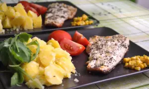 Deux assiettes de poisson grillé avec pommes de terre, tomates et maïs. Un repas sans sucre, sain et savoureux.