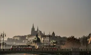 Tram jedzie przez most w Czechach, w tle widać zamek.