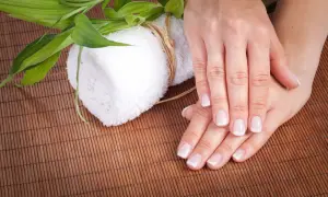 Dłonie po zabiegu pedicure japoński. Delikatne paznokcie, biały ręcznik i zielone liście bambusa na macie.