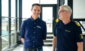 Två män ler mot varandra. Den ena bär en mörkblå skjorta med texten "Polis förbundet Bergslagen", den andra en polisuniform med texten "POLIS".