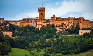 Un borgo storico su una collina verdeggiante, con una torre campanaria che domina la **città di Leopardi**.