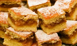 Szybkie ciasto z jabłkami, pokrojone w kostkę i posypane cukrem pudrem, wygląda apetycznie. Idealne na deser.
