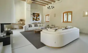 Salón moderno con sofás blancos, chimenea y suelo de microcemento sobre azulejos.