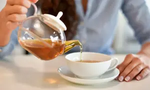 Kobieta nalewa aromatyczną herbatę z kopru włoskiego do filiżanki.