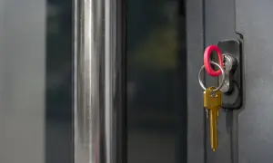 Zatrzasnięte drzwi z kluczem w zamku. Złoty klucz z czerwoną zawieszką w zamku, gotowy do otwarcia.