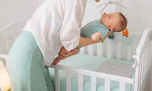 Madre acuna a su bebé dormido, listo para colocarlo en la cuna. Entender las ventanas de sueño es clave para un descanso feliz.