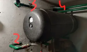 Bojler z termometrem i instalacją hydrauliczną. Widoczny odpowietrznik bojlera, zawory i rury.