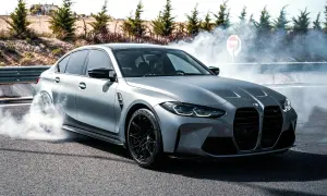 Srebrne BMW M3 G80 w poślizgu, z opon dymiących na asfalcie.