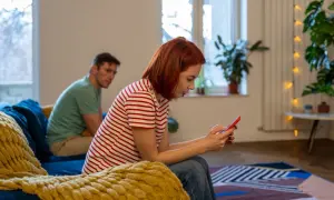 Kobieta z rudymi włosami, jak toksyczna siostra, ignoruje mężczyznę, skupiając się na telefonie.