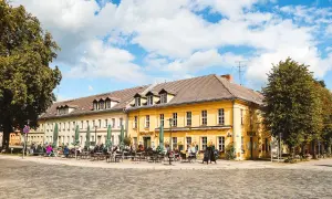 Gemütliche Straßencafés beleben die sonnige Rheinsberg Altstadt. Menschen sitzen unter grünen Sonnenschirmen vor gelben Fachwerkhäusern.