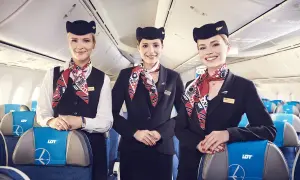 Trzy uśmiechnięte stewardessy LOT w eleganckich mundurkach. Zastanawiasz się, ile zarabia stewardessa LOT?