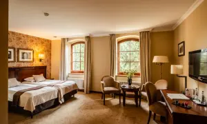 Przytulny pokój hotelowy z dwoma łóżkami, dwoma oknami i widokiem na zieleń. Idealne miejsce na wypoczynek po zwiedzaniu Wrocławia, Zamek Topacz czeka!