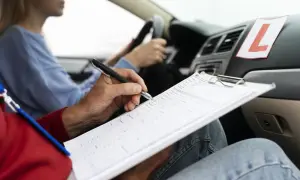 Instructor anota en un portapapeles mientras una alumna conduce. Si suspendo el práctico, ¿cuándo puedo volver a presentarme?