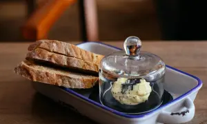Tranches de pain artisanal avec une portion de beurre aux herbes, une excellente alternative par quoi remplacer le beurre.