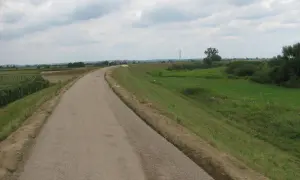 Asfaltowa ścieżka rowerowa velo raba wije się wśród pól kukurydzy i zielonych łąk, zapraszając na przejażdżkę.