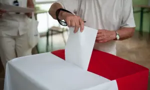 Mężczyzna wrzuca kartę do głosowania do urny. To ważny moment, nawet jeśli są to wybory poza miejscem zamieszkania.