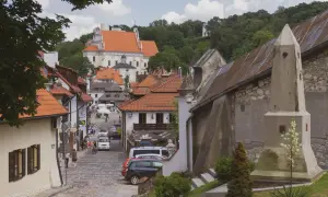 Urokliwa ulica w Kazimierzu Dolnym z kościołem na wzgórzu. Kamienne bruki, kamienice z czerwonymi dachami i zielone drzewa tworzą malowniczy krajobraz.