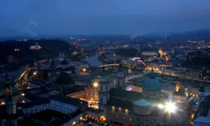 Salzburg im Winter bei Nacht. Lichter der Stadt, die Salzach und die Festung Hohensalzburg erhellen die Szene.