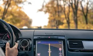 Widok z wnętrza samochodu na nawigację GPS. Kierowca trzyma kierownicę, a ekran pokazuje trasę. To dobry moment, by pomyśleć, jak zaktualizować GPS.