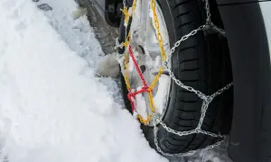 Łańcuchy na kołach 4x4 poprawiają przyczepność na śniegu. Widać je na oponie w zaspie.