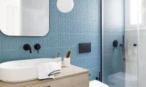 Moderno baño con azulejos azules texturizados y lavabo ovalado. Ideas para cuartos de baño pequeños: grifería negra, espejo redondeado y ducha de cristal.