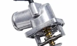 Metalowy termostat w samochodzie z widocznym mechanizmem sprężynowym i króćcem.
