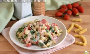Piatto di pasta fredda con salmone, pomodorini e rucola, condita con una cremosa salsa.
