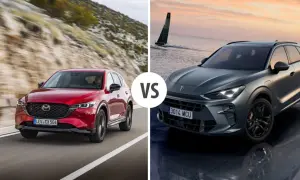 Czerwona Mazda CX jedzie po górskiej drodze, a szary SUV stoi nad wodą.