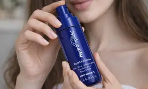 Dłonie kobiety trzymają granatową buteleczkę serum HydroPeptide z kwasem hialuronowym, obiecującą transformację skóry.