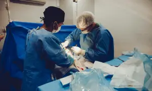Chirurdzy w sterylnych ubraniach podczas operacji, widoczne narzędzia i materiały medyczne.