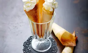 Délicieux cornets croustillants garnis de crème chantilly aérienne, prêts à être dégustés.