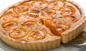 Une délicieuse tarte aux abricots, avec une part déjà servie, révèle sa garniture dorée et ses fruits juteux.