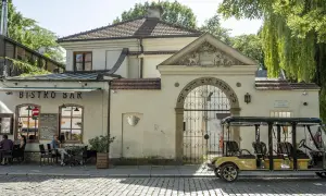 Zabytkowa brama z hebrajskimi napisami w żydowskiej dzielnicy Krakowa. Obok bistro z ogródkiem i żółty meleks.
