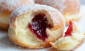 Puszyste pączki z piekarnika, oprószone cukrem pudrem, z obfitym nadzieniem z konfitury. Idealne na tłusty czwartek!