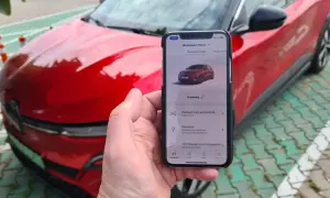 Aplikacja na telefonie pokazuje, jak przerobić auto na elektryczne, obok czerwonego samochodu.