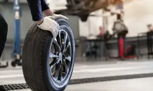 Mechanik w rękawiczkach trzyma oponę. Czy opony rowerowe do miasta z gładkim bieżnikiem zużywają się szybciej na kostce i asfalcie?