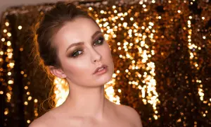 Oczy kobiety błyszczą jak złoto, a jej makijaż w odcieniach vanilla jaki to kolor podkreśla jej urodę na tle migoczących świateł.