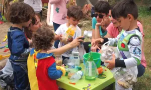 Niños disfrutan de actividades infantiles al aire libre, jugando con materiales reciclados y aprendiendo.