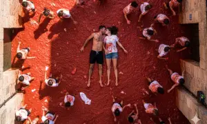 Para zakochanych całuje się pośród tłumu ludzi rzucających pomidorami podczas La Tomatina w Hiszpanii.