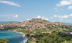Widok na malowniczą wioskę z zamkiem na wzgórzu, położoną nad turkusowym morzem. To urokliwy zakątek wyspy Lesbos, Grecja.
