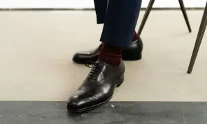 Eleganckie, czarne półbuty męskie na sznurówki, które powinien mieć w domu każdy mężczyzna, w połączeniu z bordowymi skarpetkami.