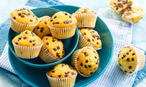 Muffin con gocce di cioccolato, dorati e invitanti, serviti in una ciotola blu.