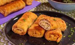 Chrupiące krokiety z kapustą i pieczarkami, posypane szczypiorkiem, czekają na talerzu. Obok miseczka z barszczem.