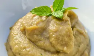 Patè di melanzane cremoso, perfetto per crostini, guarnito con foglie di menta fresca.