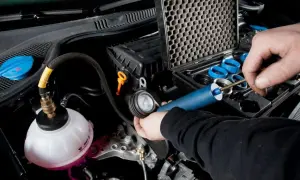 Controllo del radiatore macchina con kit di prova. Un tecnico usa uno strumento per verificare la pressione del sistema di raffreddamento.