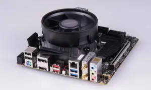 Mainboard mit AMD-Kühler, bereit für einen Ryzen 5 2400G Prozessor. Anschlüsse für USB, HDMI, LAN und Audio sind sichtbar.